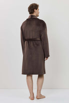 Person wearing a brown robe standing against a white background