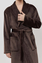 Man wearing a brown robe against a white background