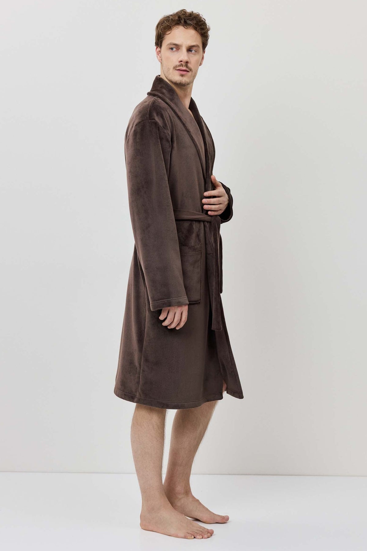 Man wearing a brown robe standing against a white background