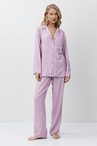 Woman wearing a lilac striped pajama set on a white background