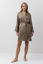 Woman wearing a brown satin gown against a white background
