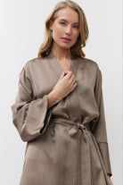 Woman wearing a beige satin gown against a white background