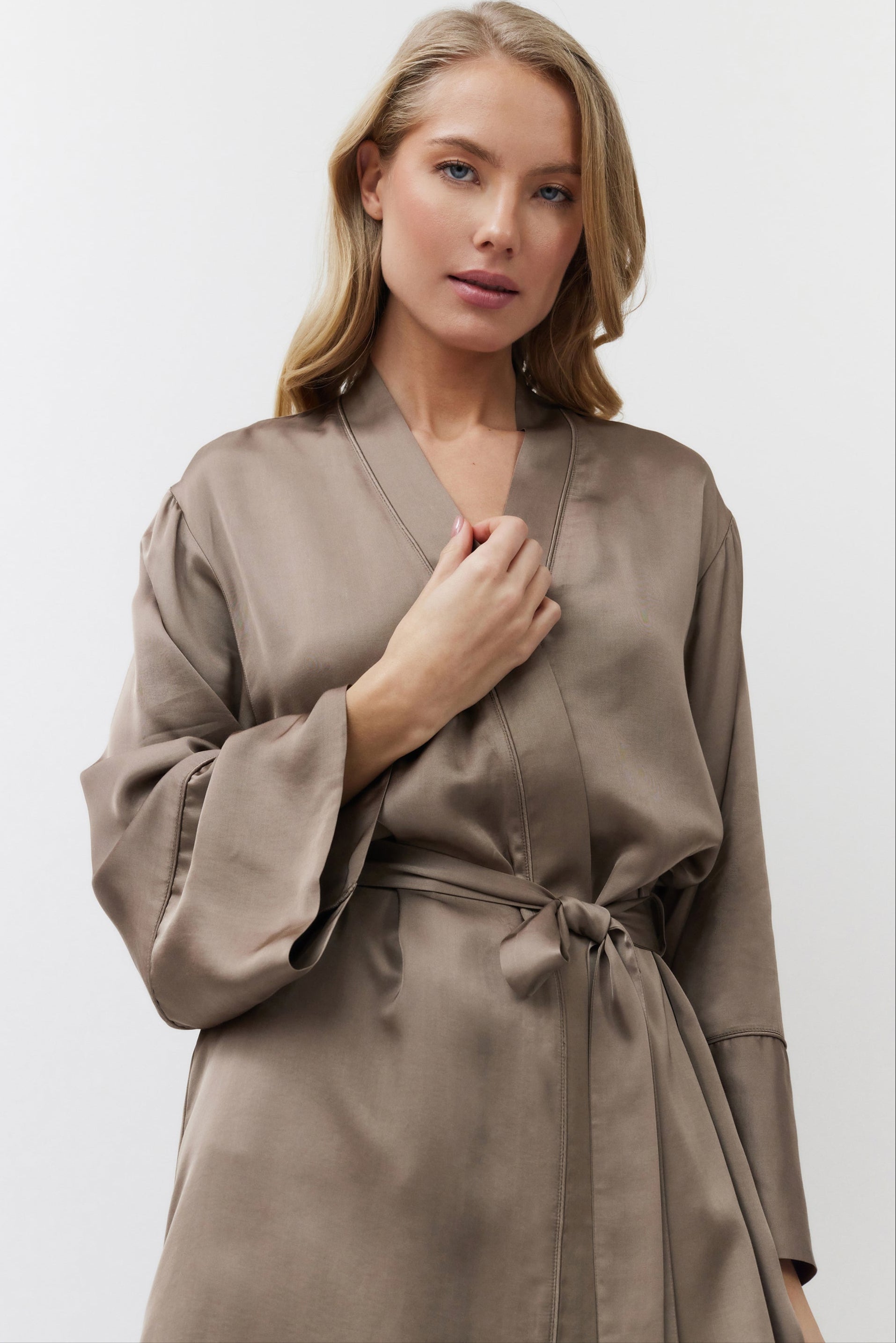 Woman wearing a beige satin gown against a white background