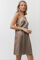 Woman wearing a brown nightdress with lace details on a white background