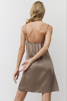 Woman wearing a brown satin nightdress against a plain background
