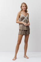 Woman wearing a brown lace top and shorts set on a white background