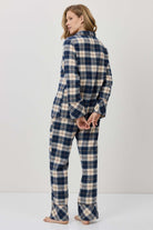 Woman wearing a blue and white plaid pajama set against a plain background