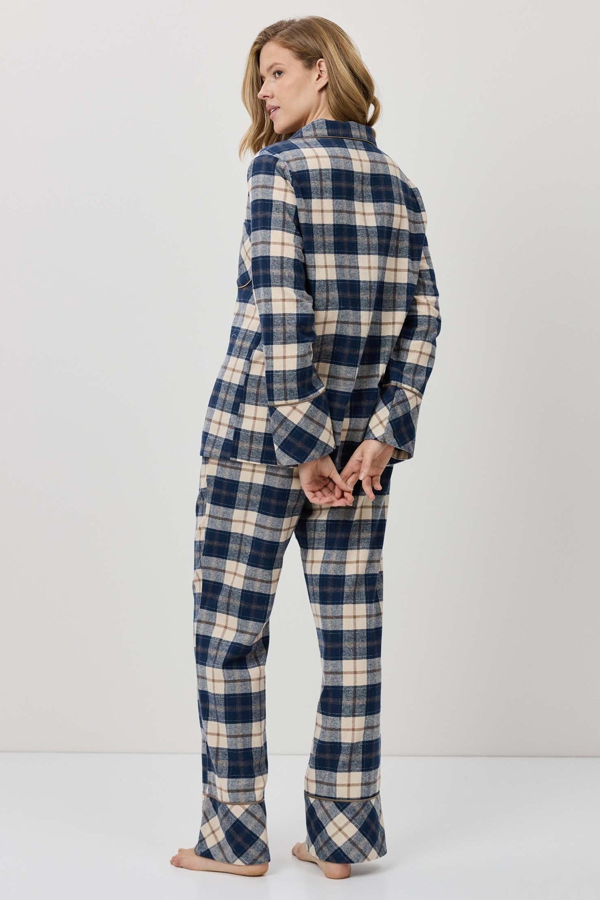 Woman wearing a blue and white plaid pajama set against a plain background