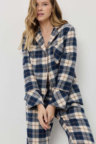 Woman wearing a blue and beige plaid pajama set against a white background