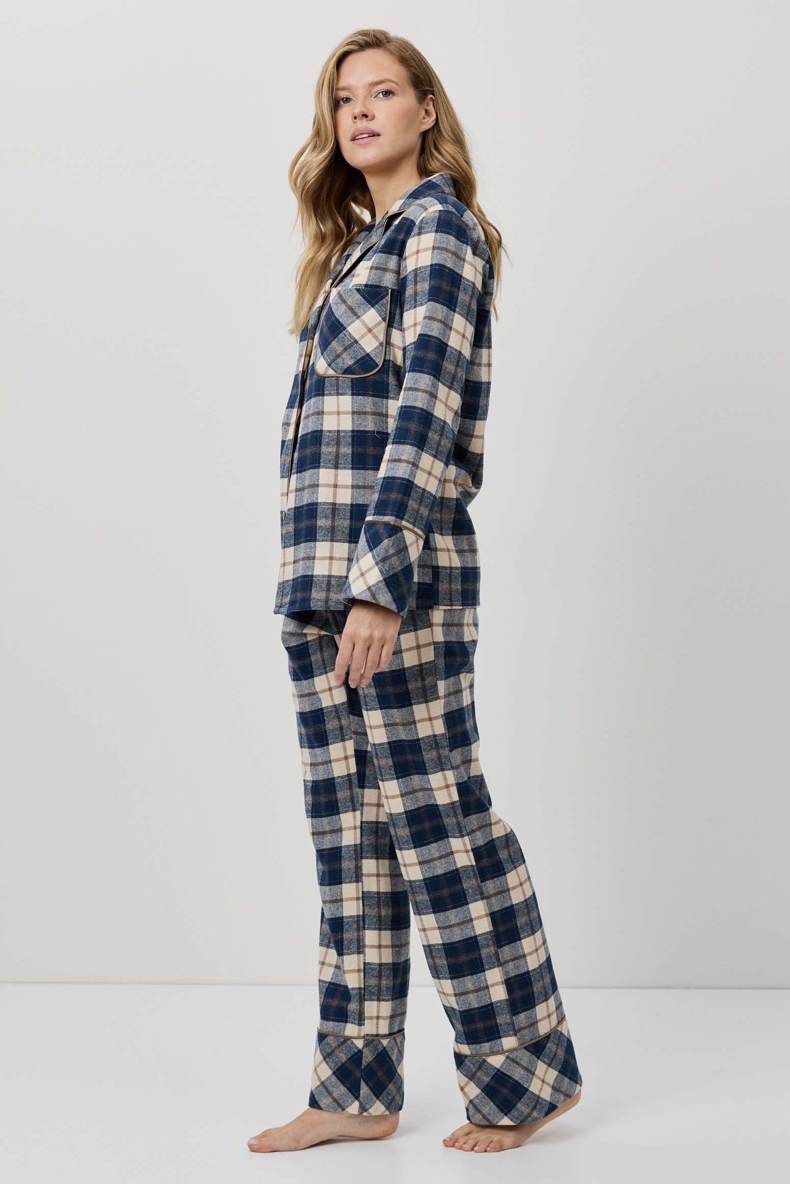 Woman wearing a blue and beige plaid pajama set against a white background