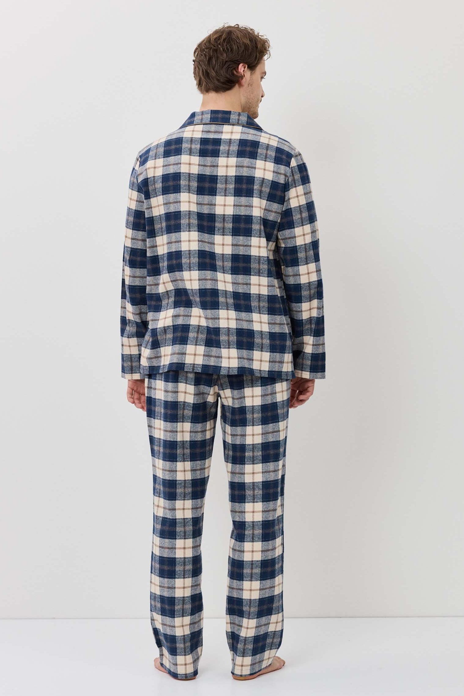 Person wearing a blue and white plaid pajama set against a white background