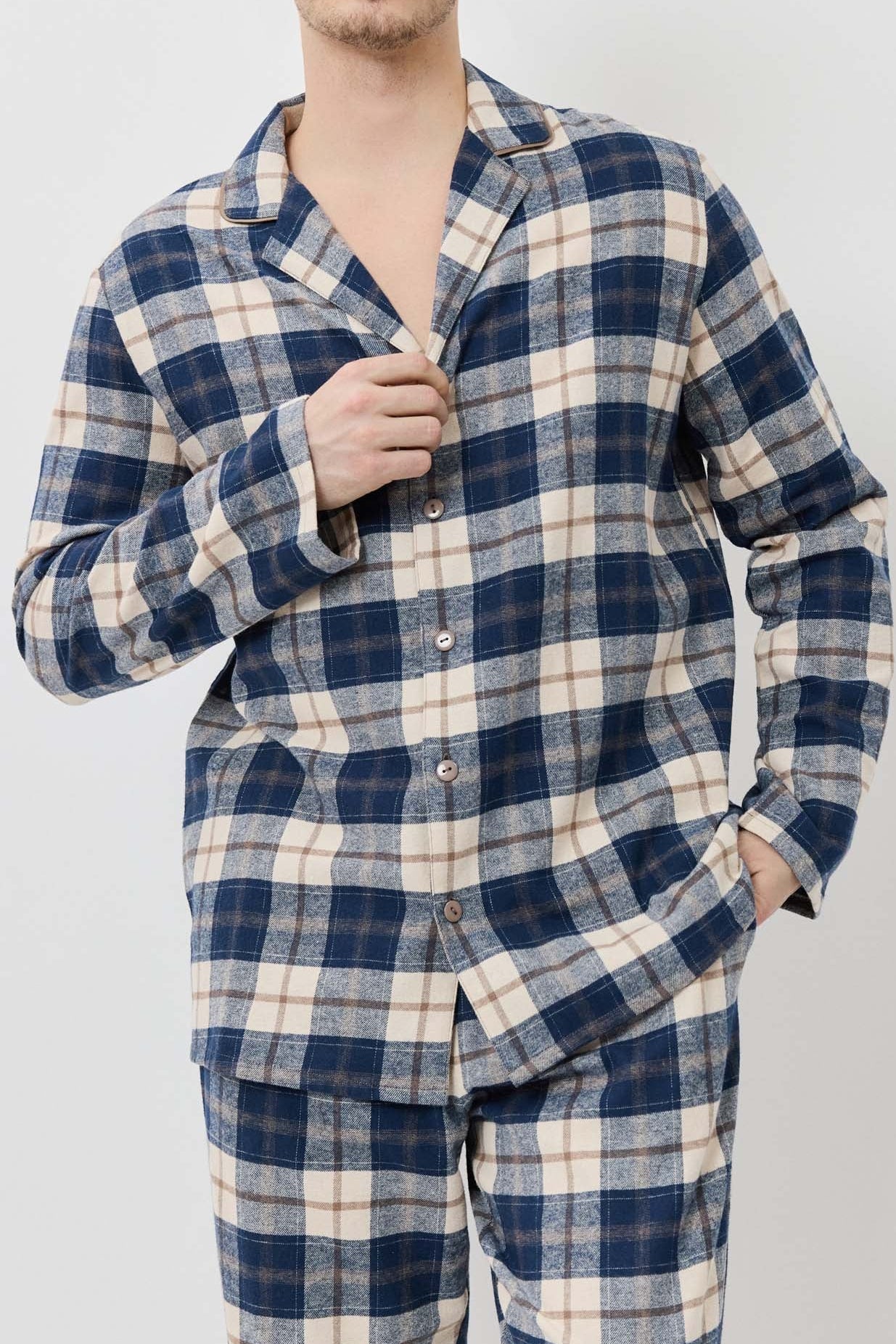 Man wearing a blue and white plaid pajama set against a plain background