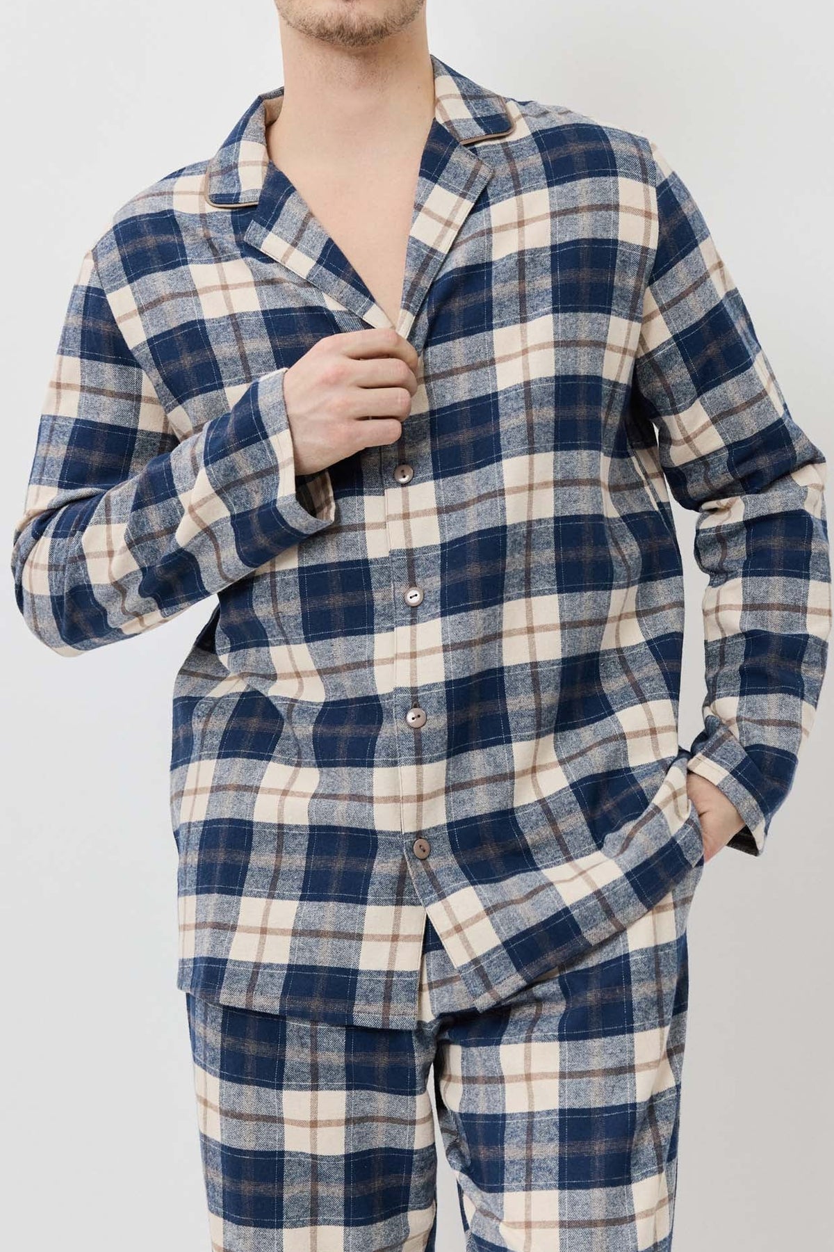Man wearing a blue and white plaid pajama set against a plain background