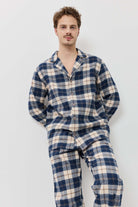 Man wearing a blue and white plaid pajama set against a plain background