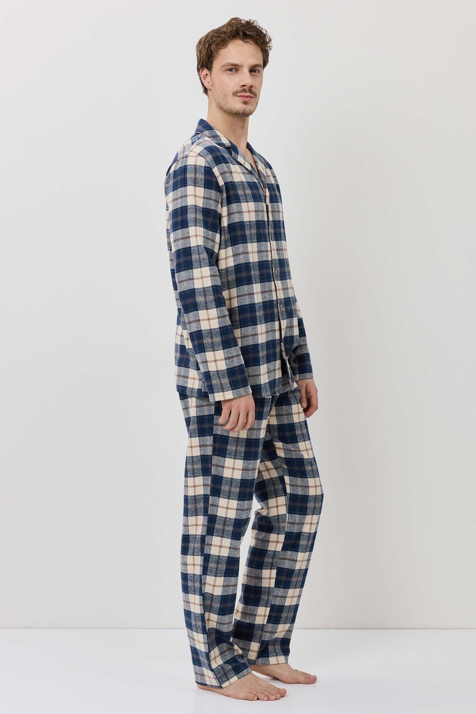 Man wearing a blue and beige plaid pajama set on a white background