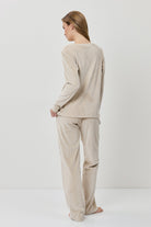 Woman wearing a beige long-sleeve top and pants on a white background