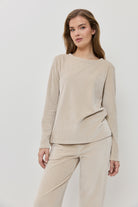 Woman wearing a beige ribbed sweater and pants on a white background