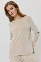 Woman wearing a beige ribbed sweater and pants on a white background