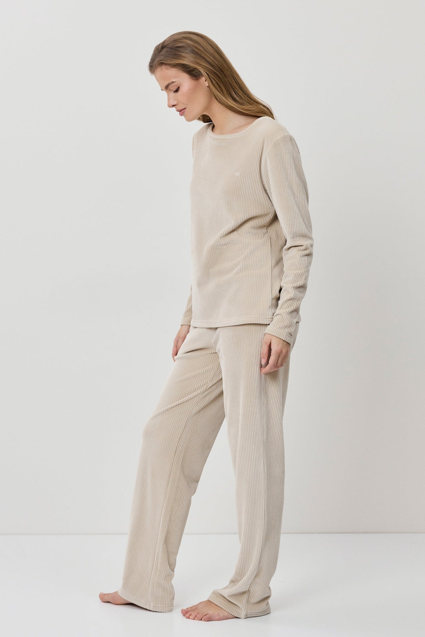 Woman wearing a beige outfit standing against a white background
