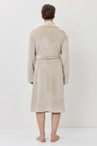 Person wearing a beige robe standing against a white background