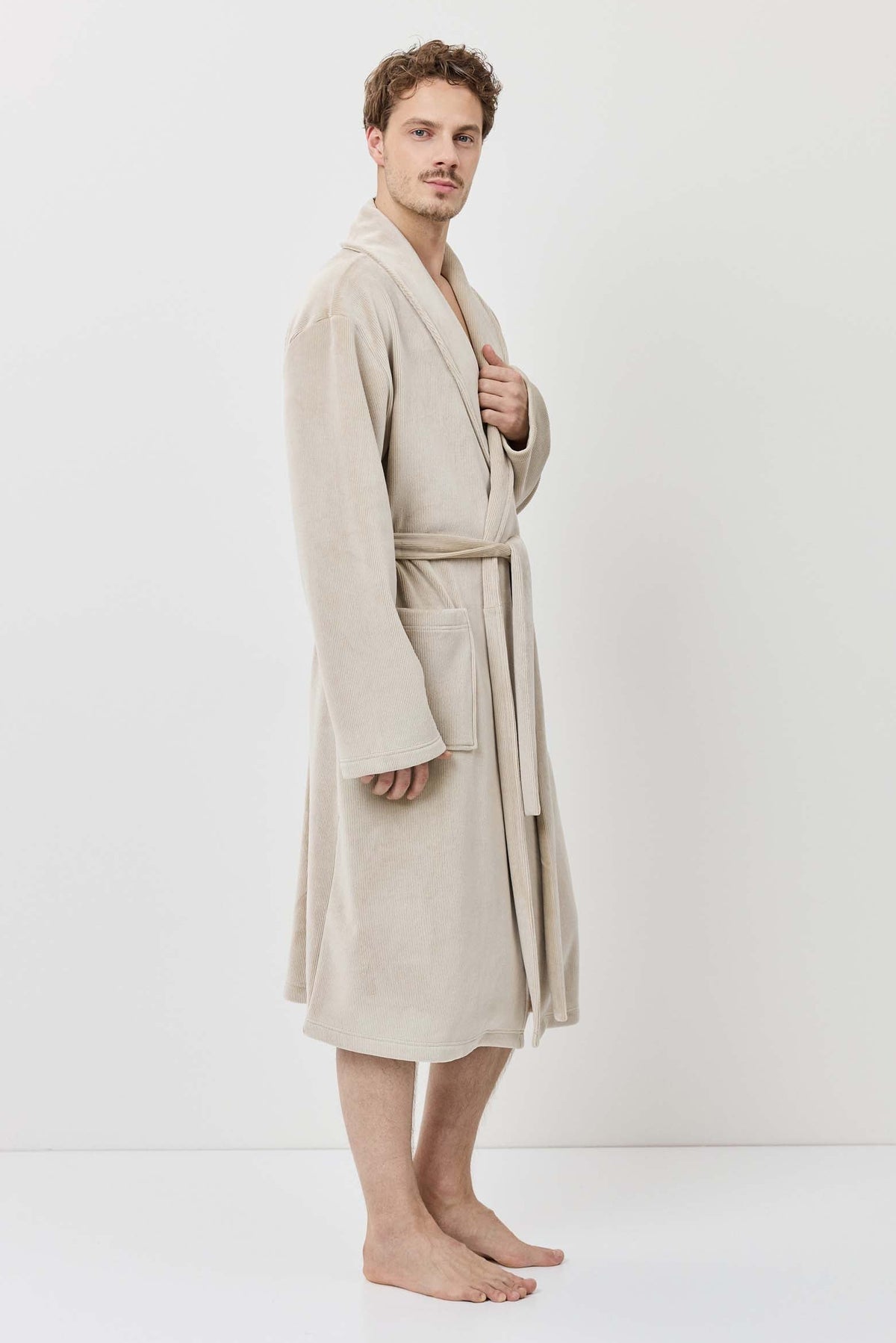 Man wearing a beige robe against a white background