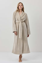 Woman wearing a beige robe against a white background
