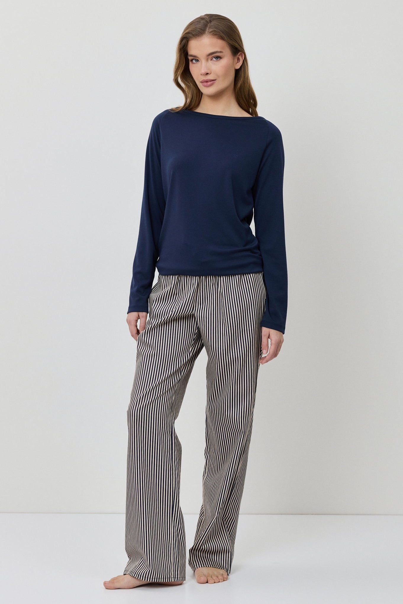 Woman wearing a navy sweater and gray checkered pants on a white background