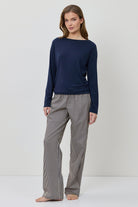 Woman wearing a navy sweater and gray checkered pants on a white background