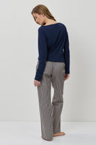Woman wearing a navy sweater and gray striped pants on a white background