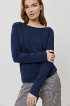 Woman wearing a navy blue sweater and striped pants on a light gray background