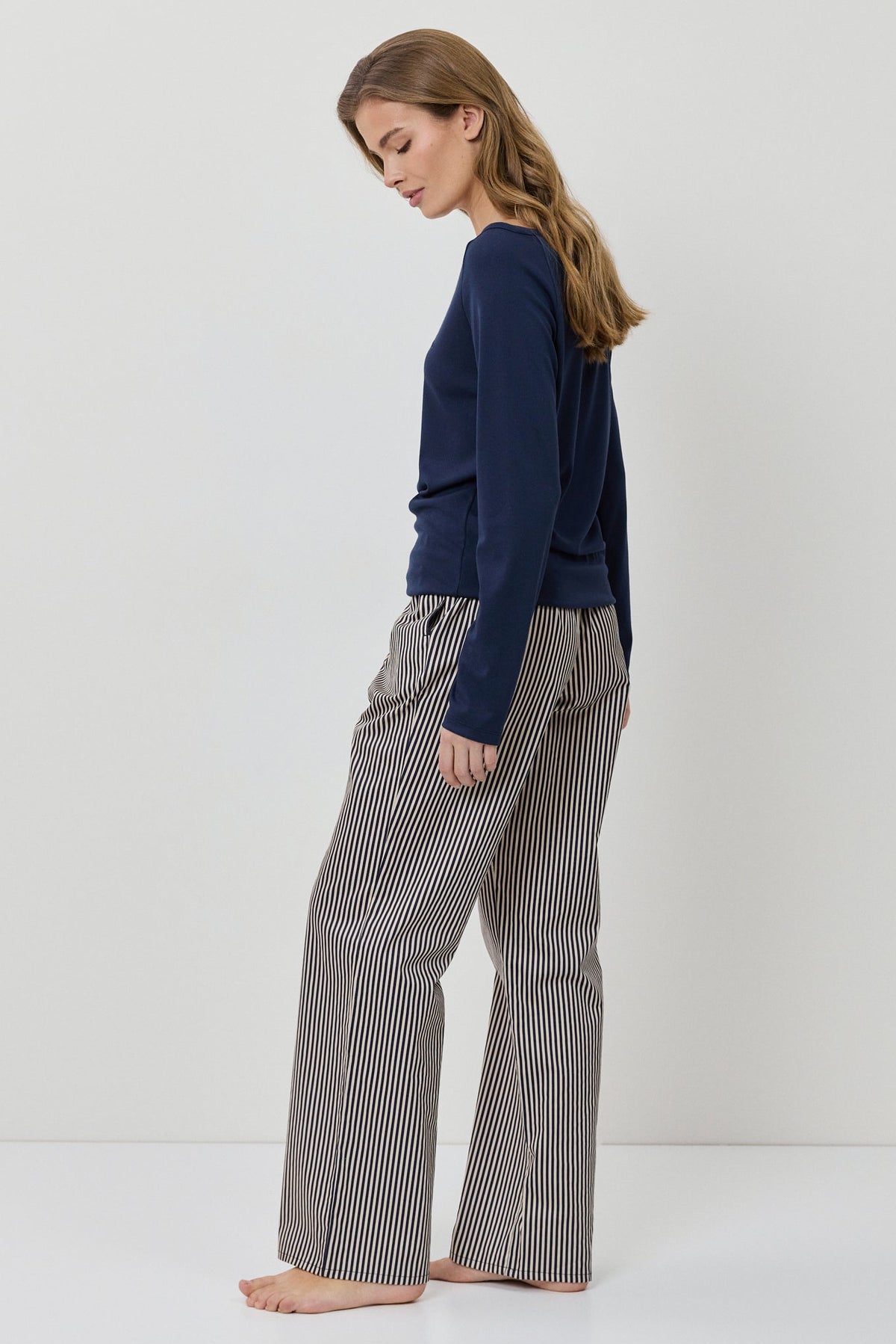 Woman wearing a navy sweater and gray checkered pants on a white background