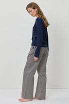 Woman wearing a navy sweater and gray checkered pants on a white background
