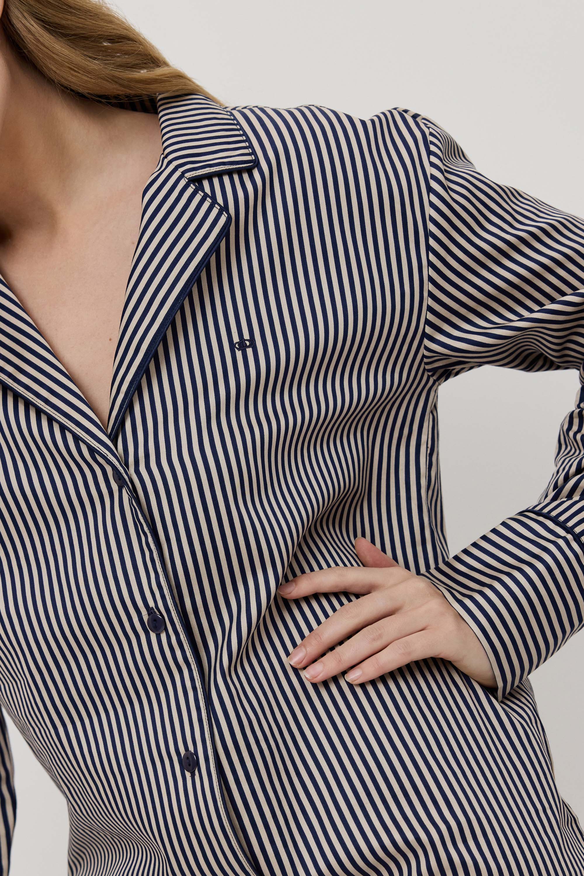 Woman wearing a navy and white striped shirt against a neutral background
