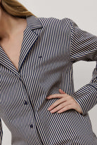 Woman wearing a navy and white striped shirt against a neutral background