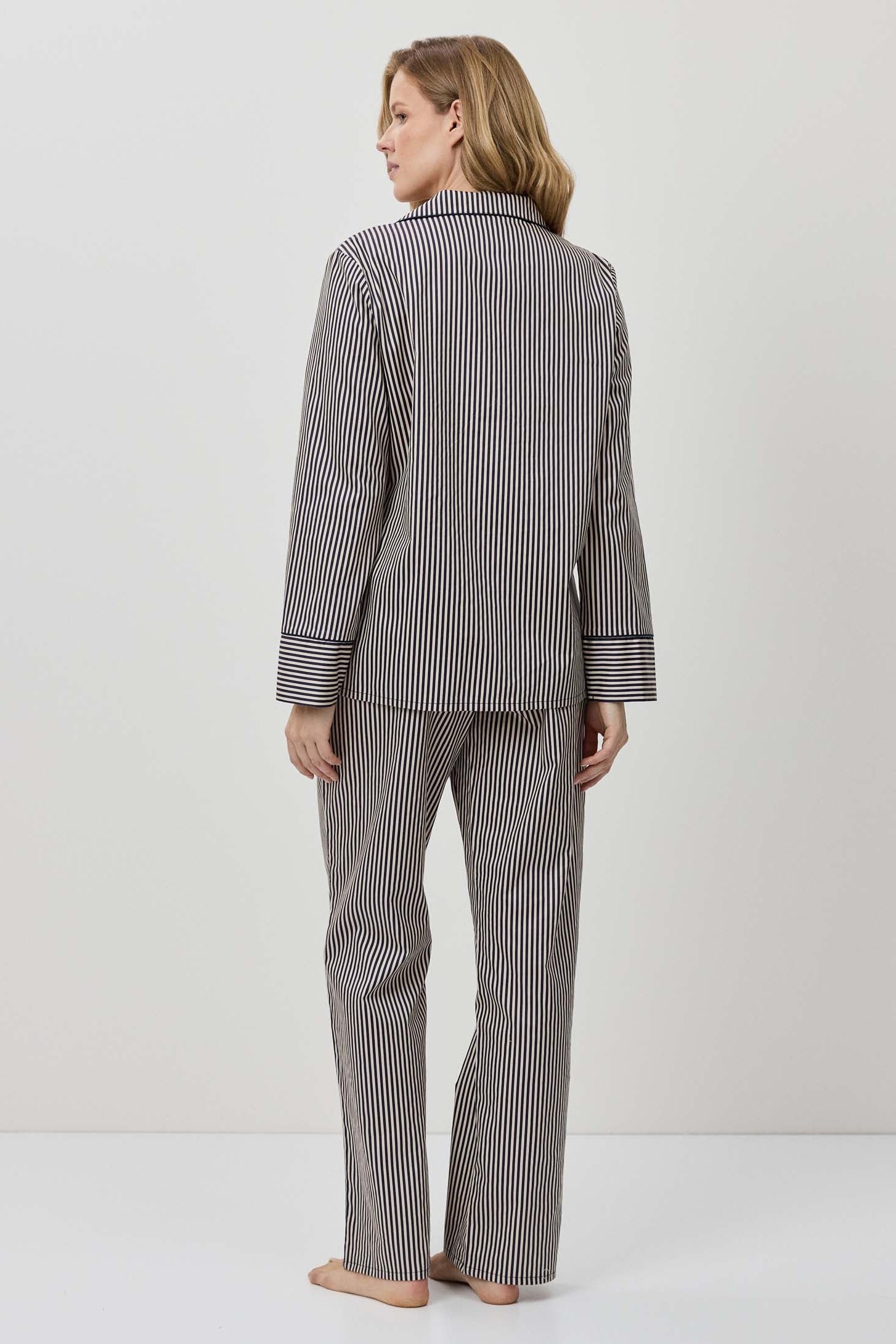 Woman wearing a gray striped pajama set against a white background