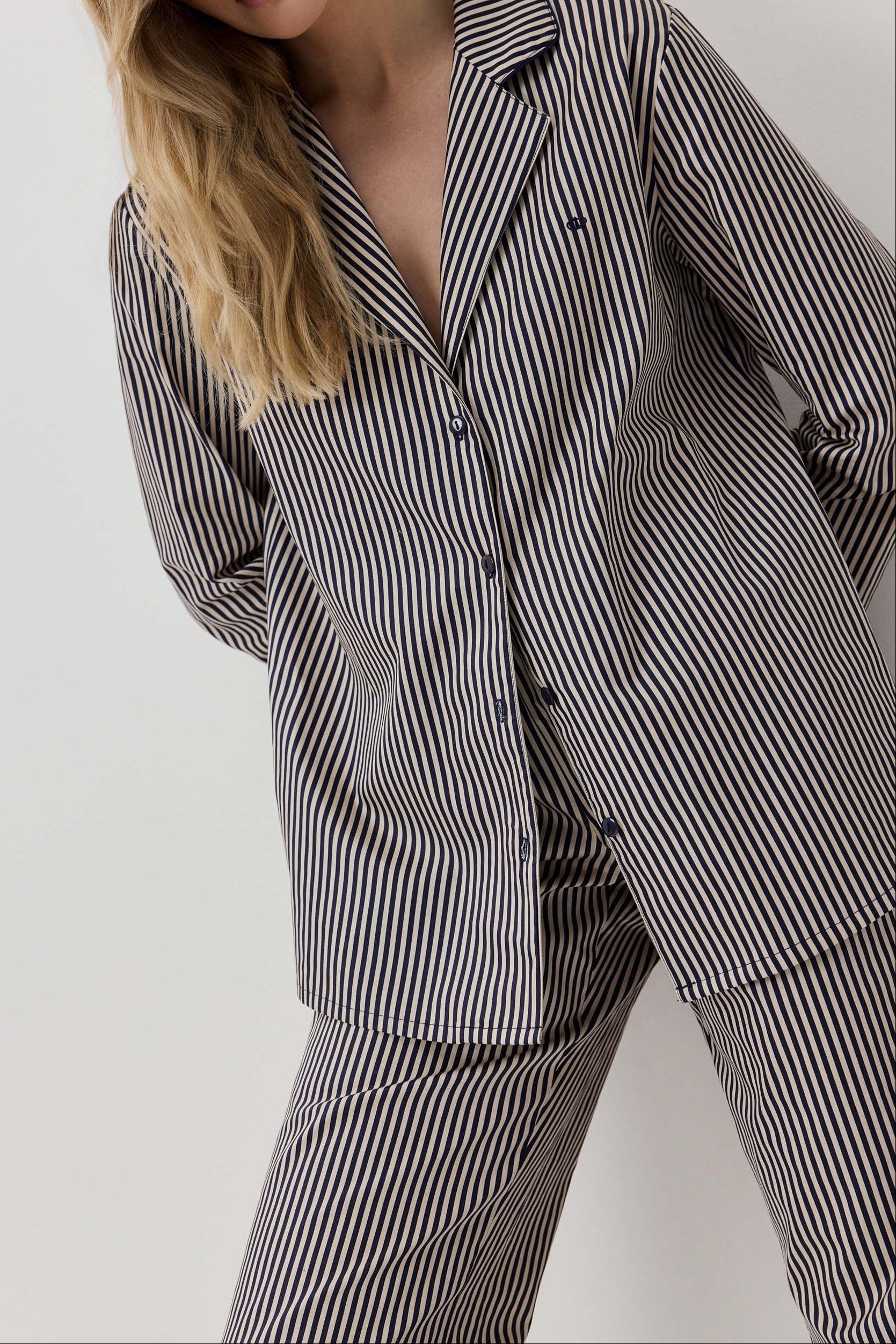 Woman wearing a black and white striped pajama set against a plain background