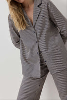 Woman wearing a black and white striped pajama set against a plain background