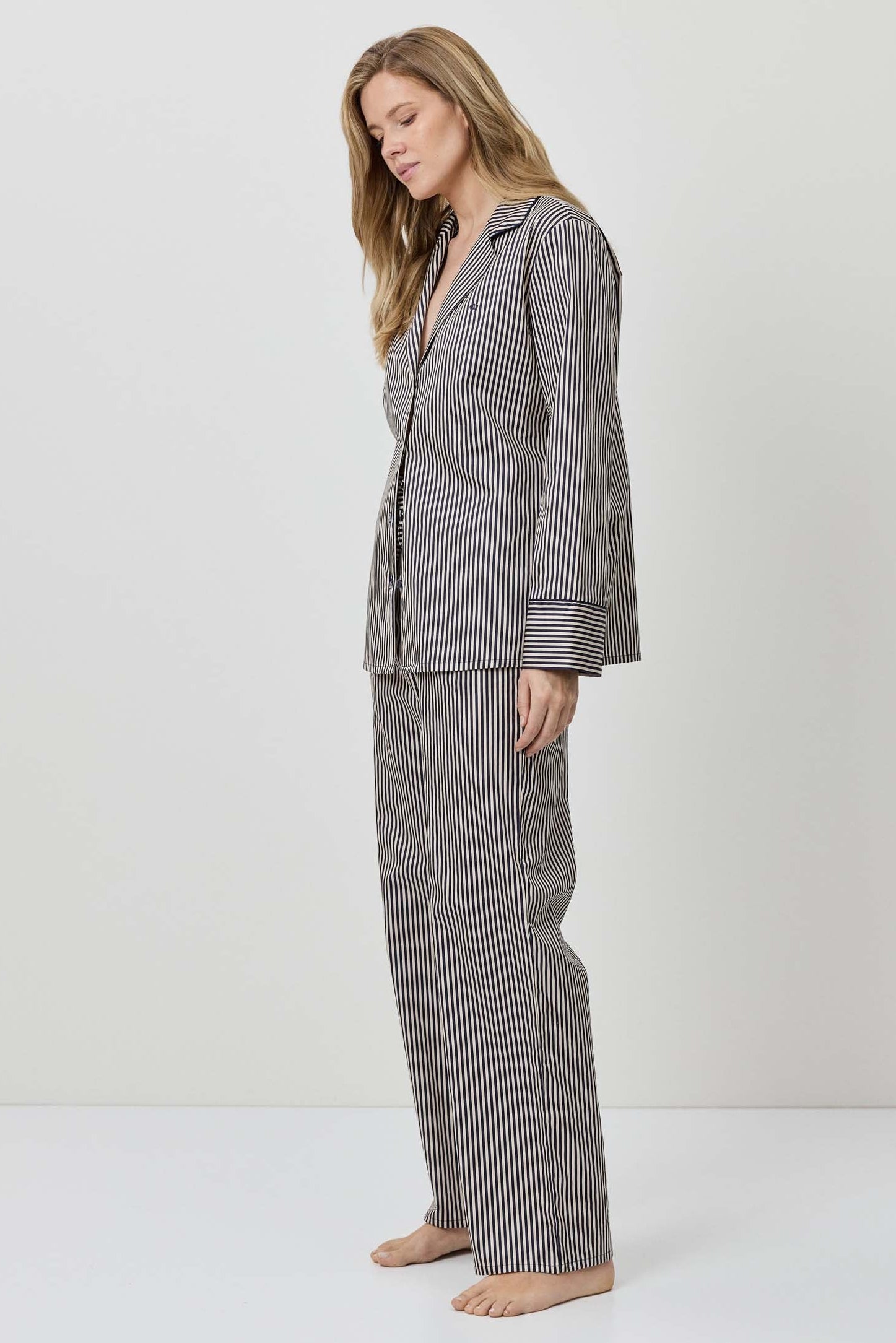 Woman wearing a gray striped pajama set on a white background