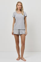 Woman wearing a gray pajama set on a white background