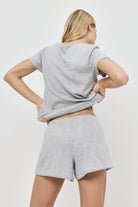 Person wearing a gray pajama set with shorts set on a white background