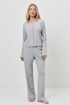Woman wearing a gray pajama set against a white background