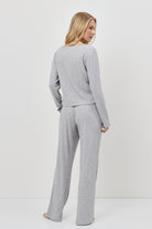 Woman wearing a gray pajama set standing against a white background