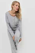 Woman wearing a gray pajama set against a white background