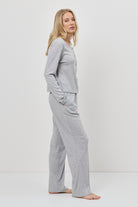 Woman wearing a gray pajama set against a white background