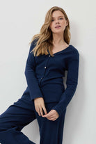 Woman wearing navy blue pajamas against a white background