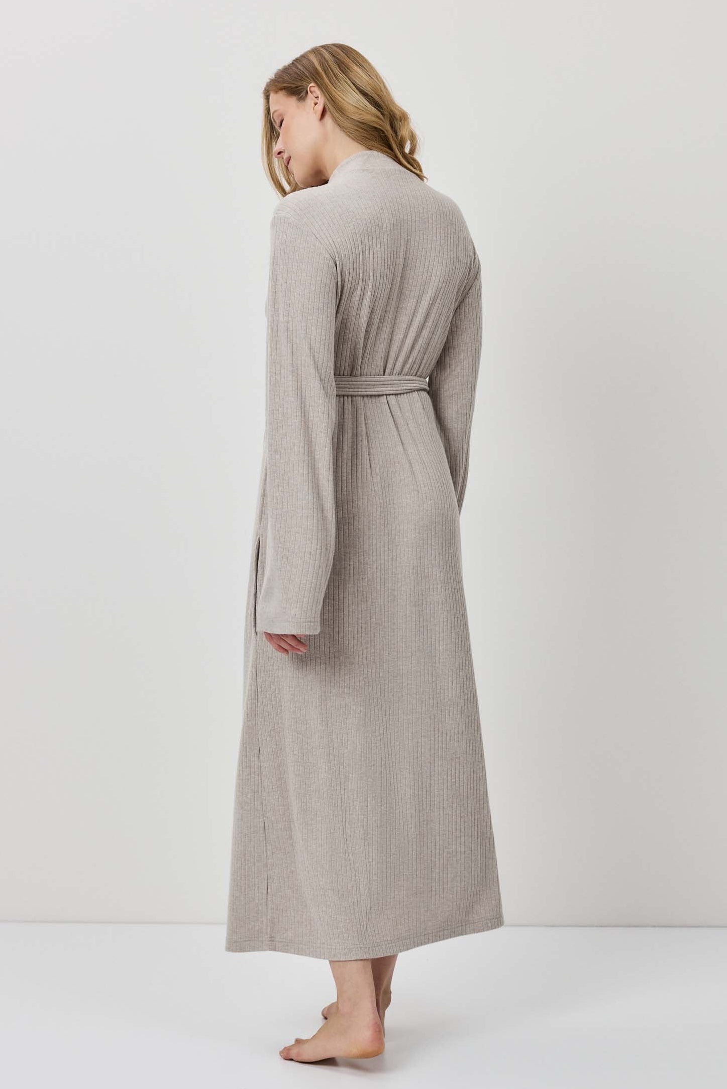 Woman wearing a long beige robe against a white background