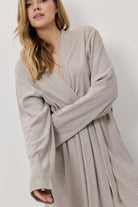 Woman wearing a beige robe against a white background