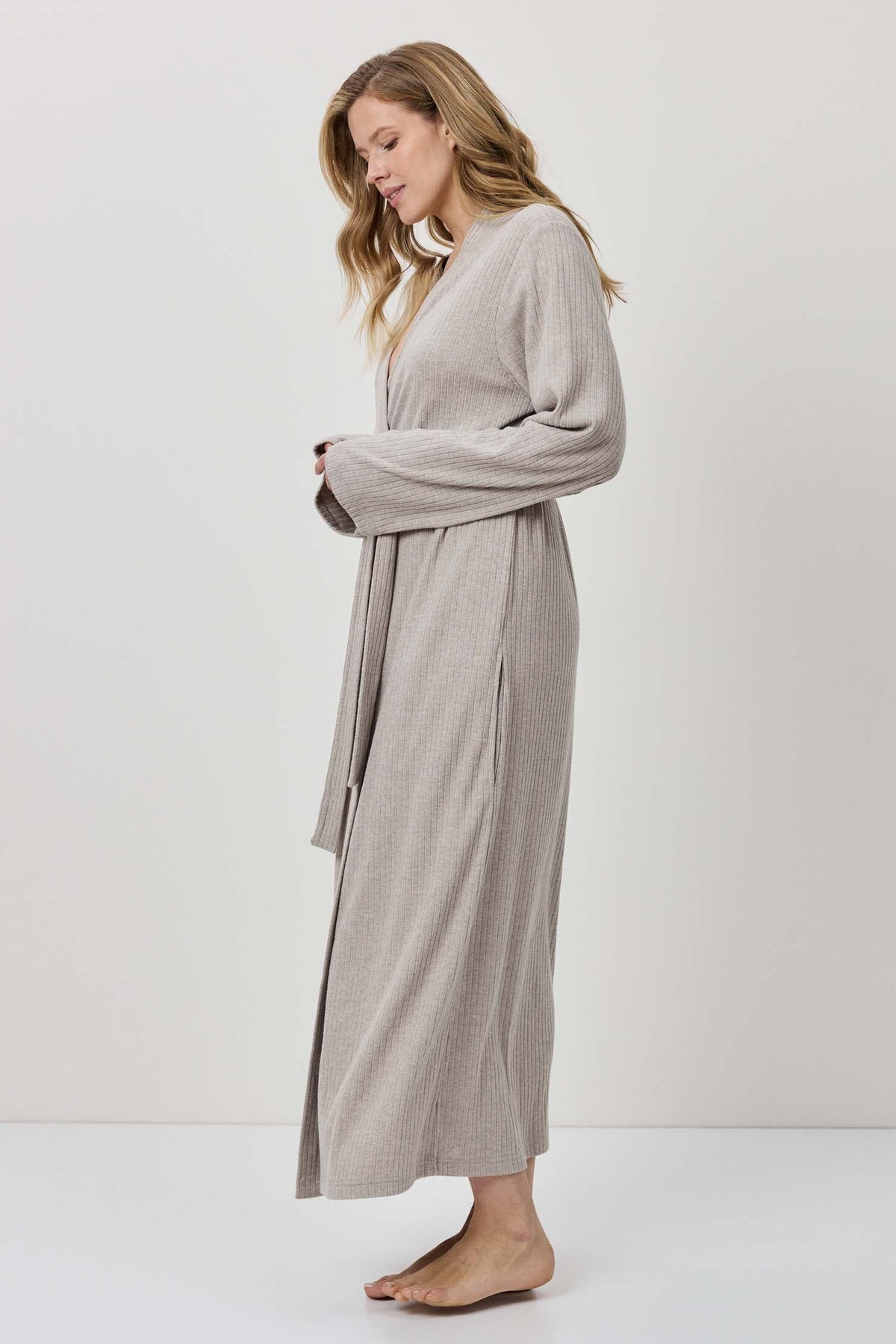 Woman wearing a long beige robe against a white background