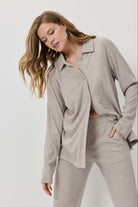 Woman wearing a beige ribbed pajama set against a white background