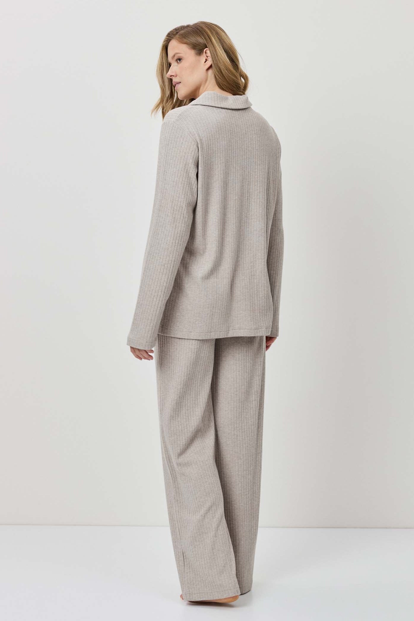 Woman wearing a beige suit standing against a white background